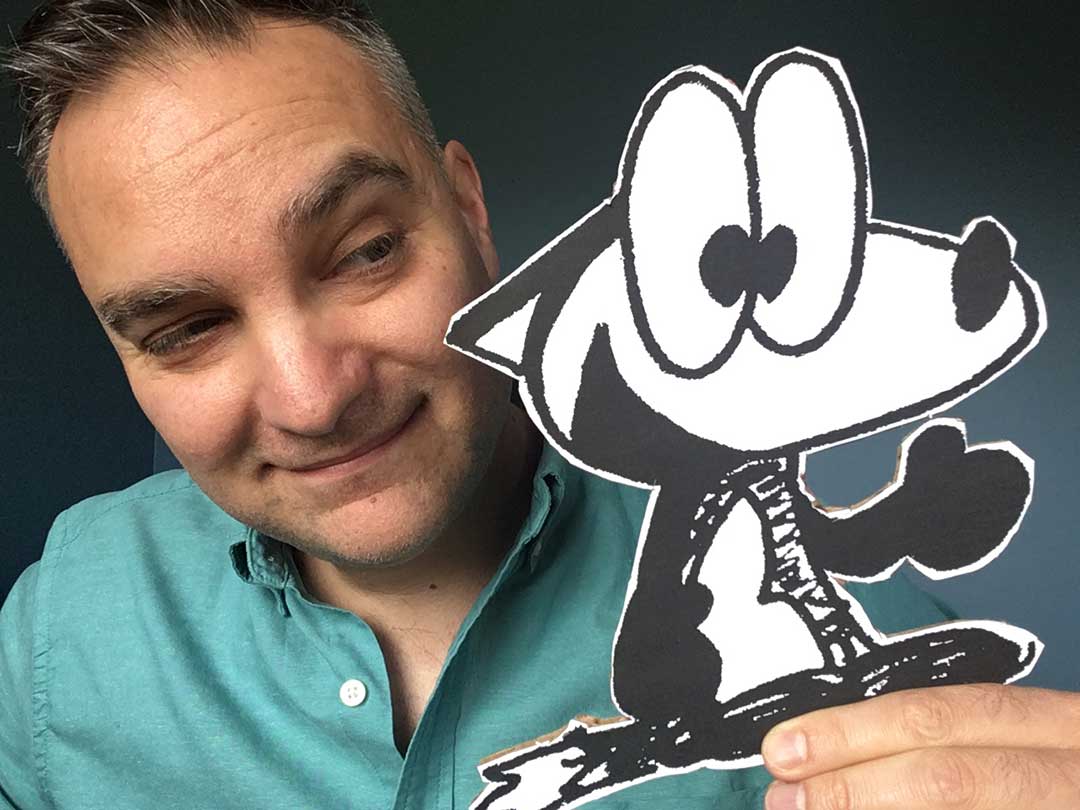 A man with short hair smiling at a cardboard cut out of a cartoon fox